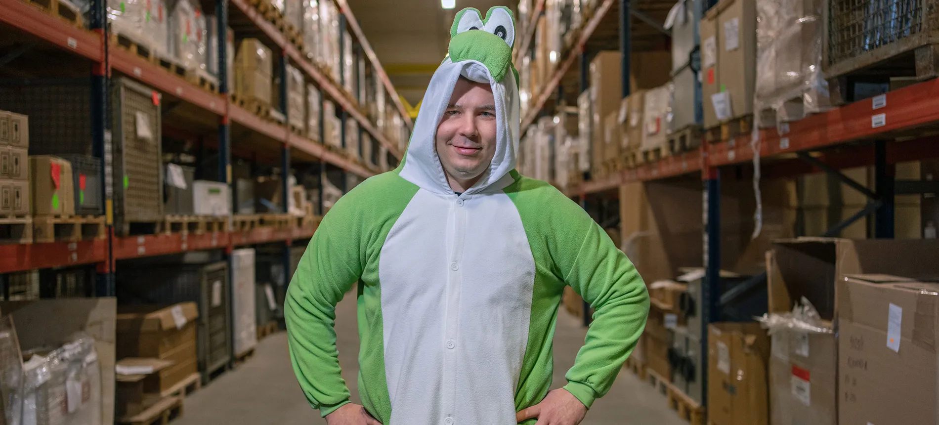 Mitarbeiter im Lagerbereich mit humorvollem Kostüm während einer Teamaktion.