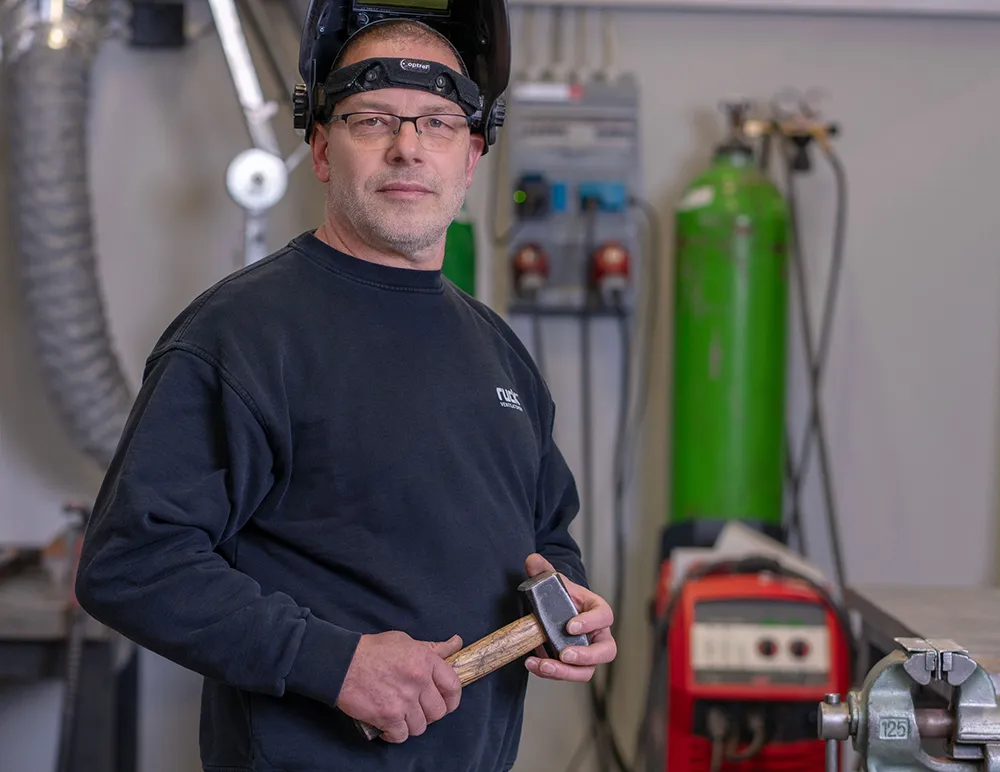 Horst arbeitet an einem Bauteil in der Produktionsumgebung.