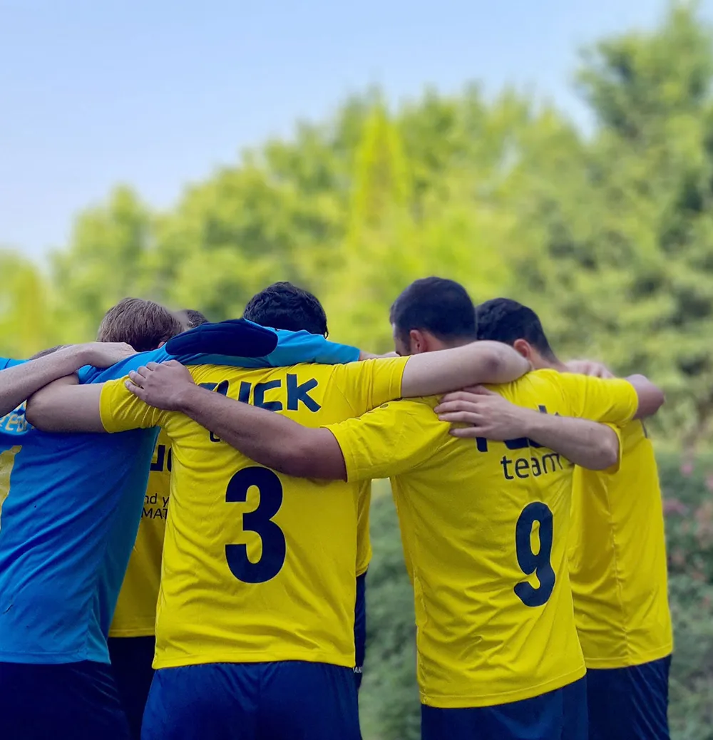 Mitarbeiter eines ruck Teams stehen eng zusammen auf einem Fußballfeld und demonstrieren Teamgeist und Zusammenhalt.